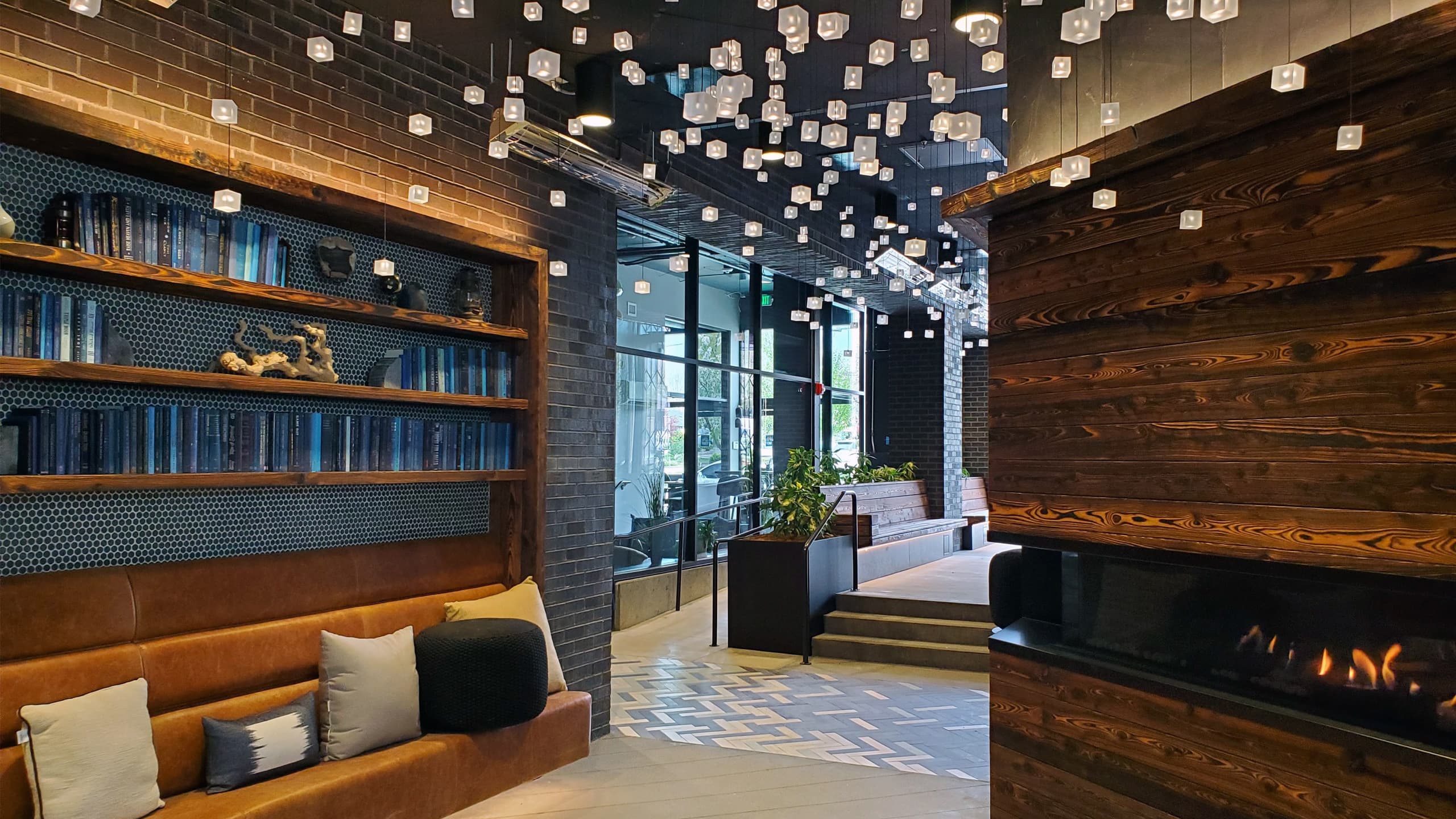 A timber and brick lobby under a scatter of pendant lights