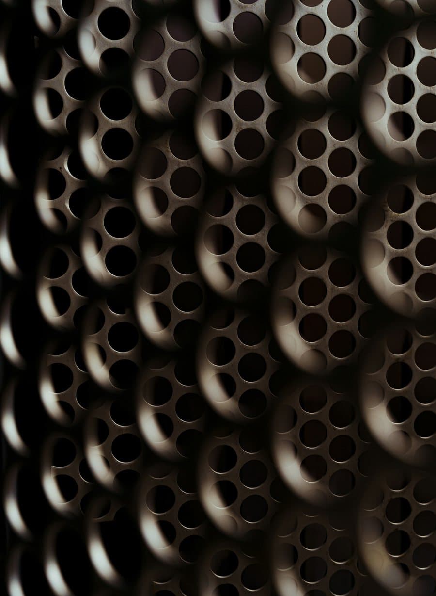 Dense array of perforated metal tubes catching raking light